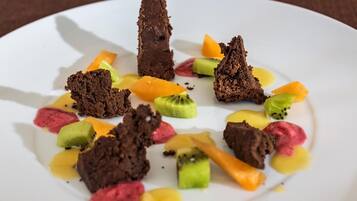 Un plato de postre con trozos de chocolate y rodajas de fruta.