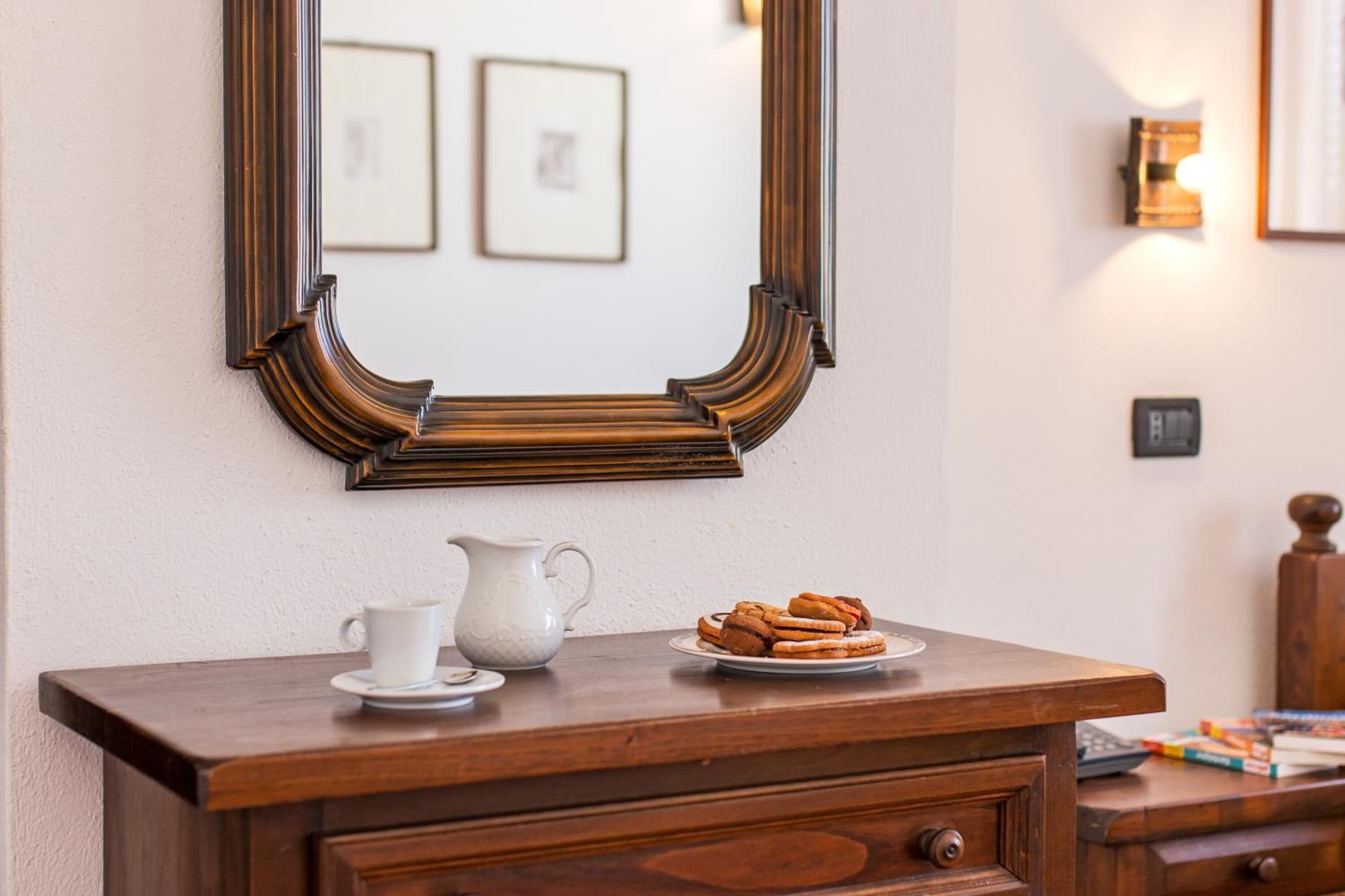 A wooden dresser with a mirror, a white pitcher, and a plate of cookies.