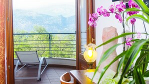 Un balcón con una silla, una mesa con lámpara y vistas a colinas verdes.
