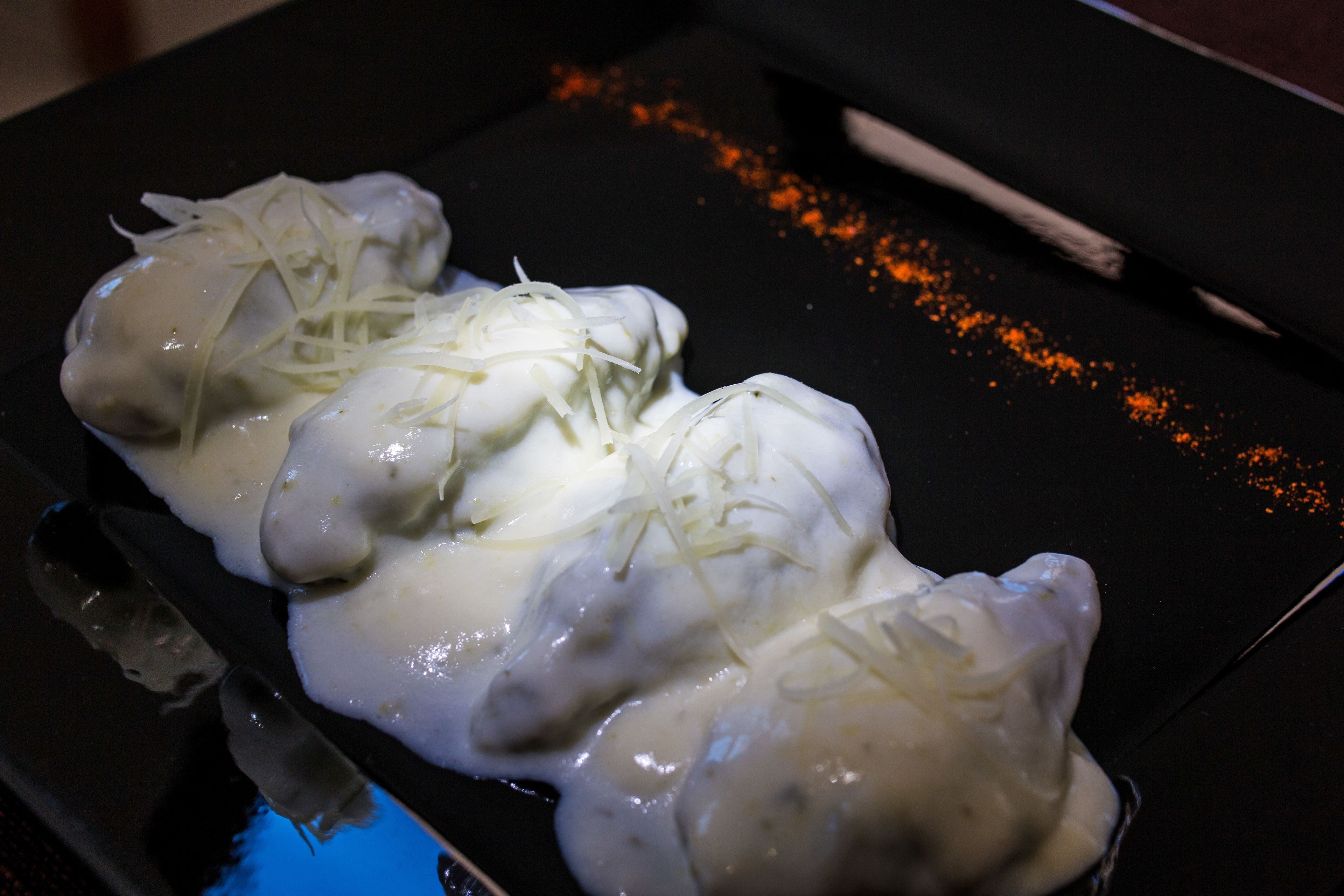 A tray with food items covered in sauce and garnished with shredded cheese.