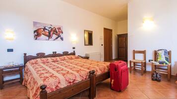 Quarto com cama de madeira, mala vermelha e cadeira com uma mochila.