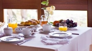 Una mesa de desayuno servida con cruasanes, fruta y jugo de naranja.
