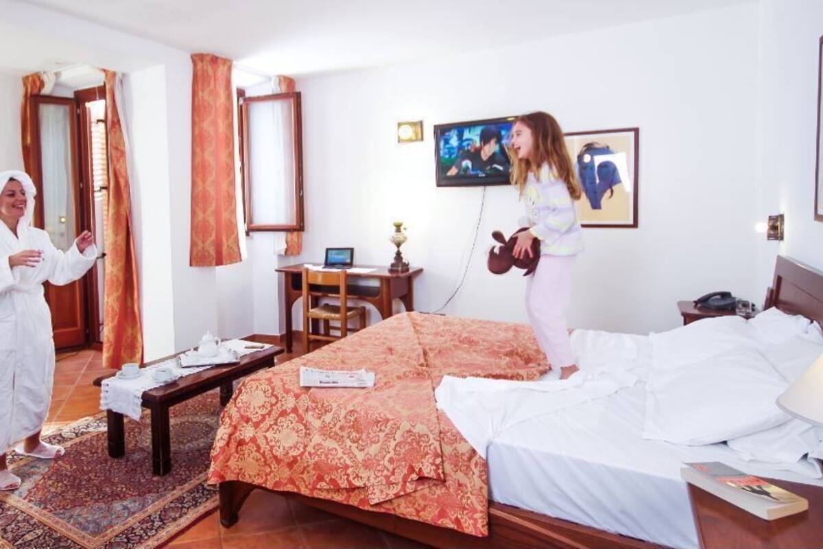 A hotel room with a bed, a desk, a TV, and a sofa.