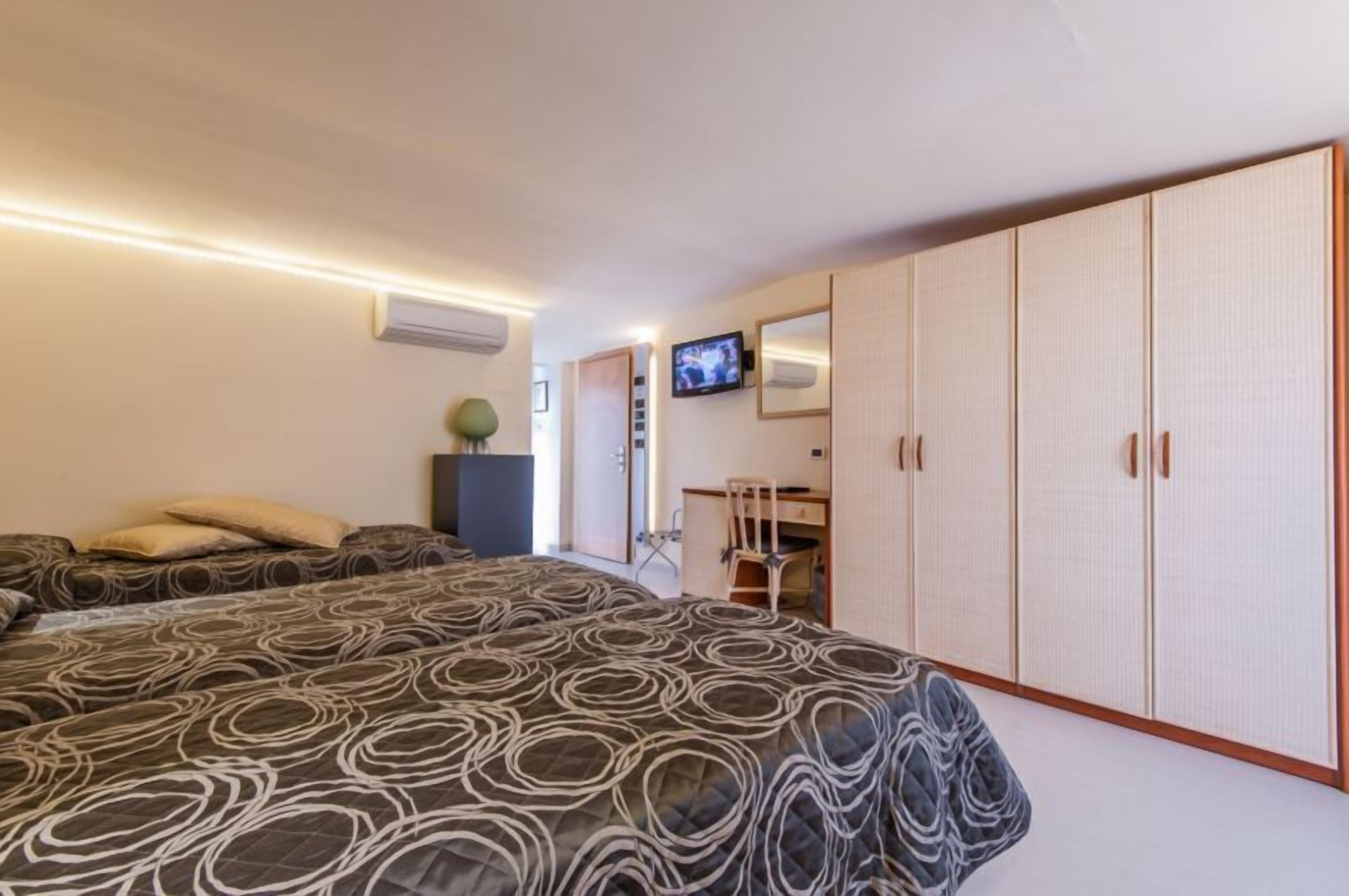Un dormitorio con una cama grande, un escritorio, una silla y un armario.