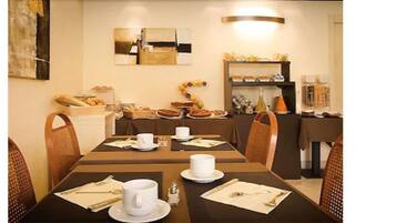 A dining area with tables set for breakfast, including bread, pastries, and coffee.