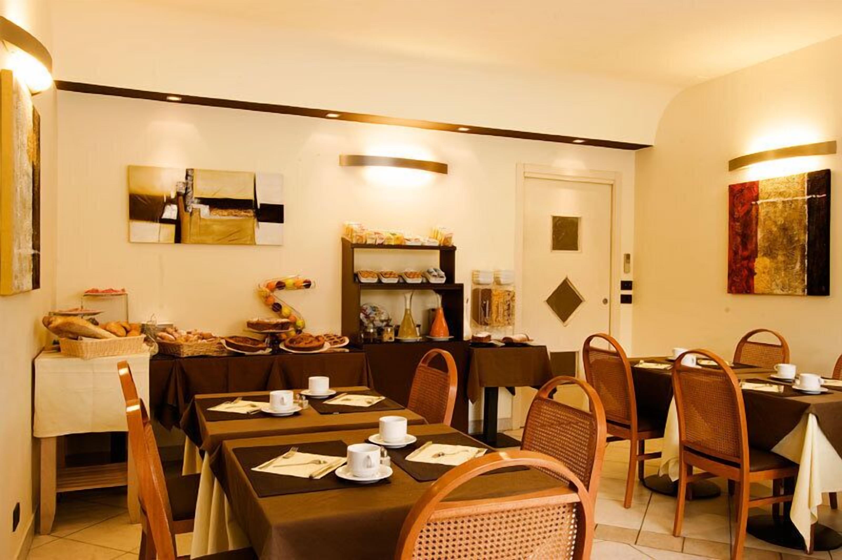 Zona de dinar amb taules preparades per l'esmorzar, un bufet amb diversos plats i una zona de cafè.