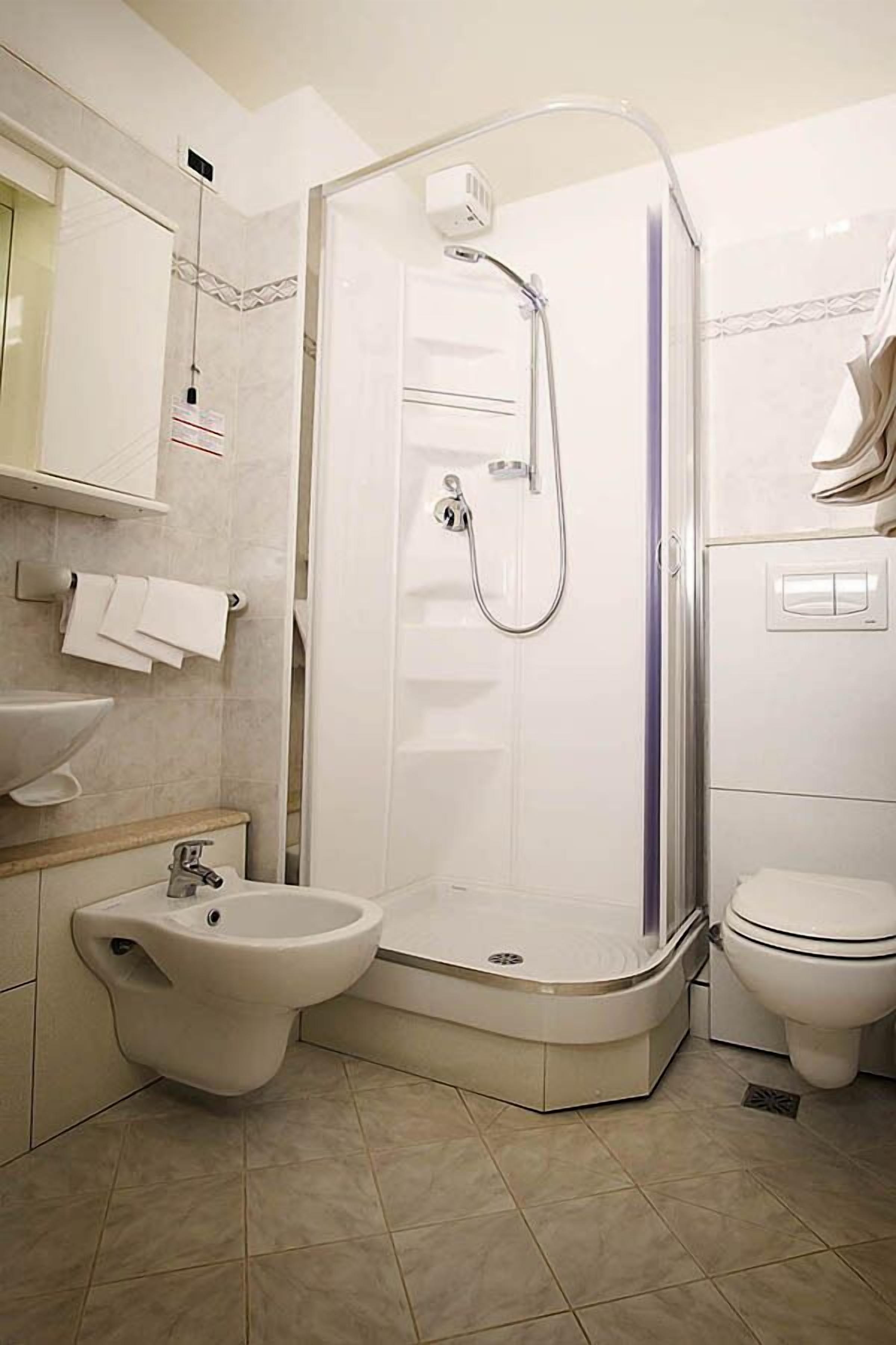 Un baño moderno con ducha de vidrio, un bidé, un inodoro y un lavamanos.