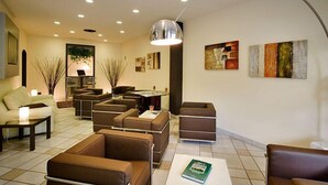 A modern lounge area with sofas, a coffee table, and a lamp. - Hotel Montebello (Montecatini Terme)