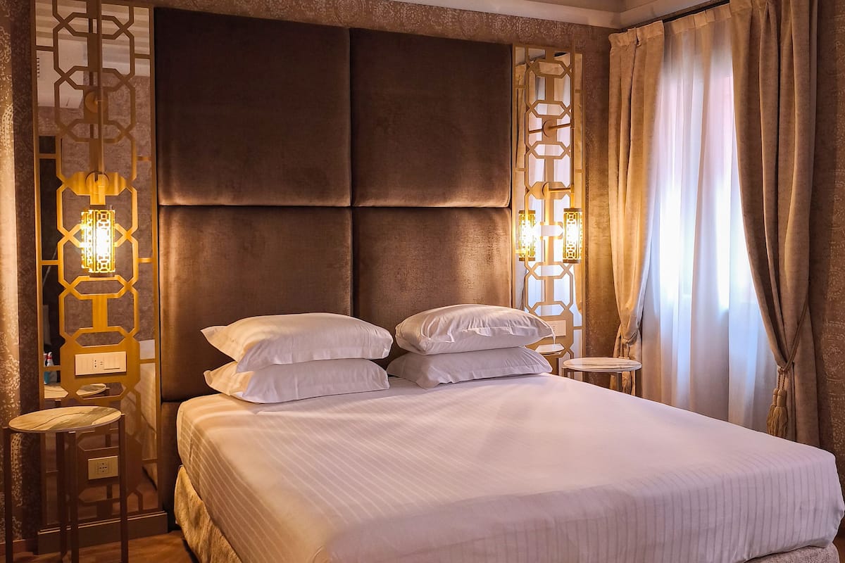 Ein Hotelzimmer mit einem großen Bett, zwei Nachttischen, einer Kopfteil und einem Holzboden.
