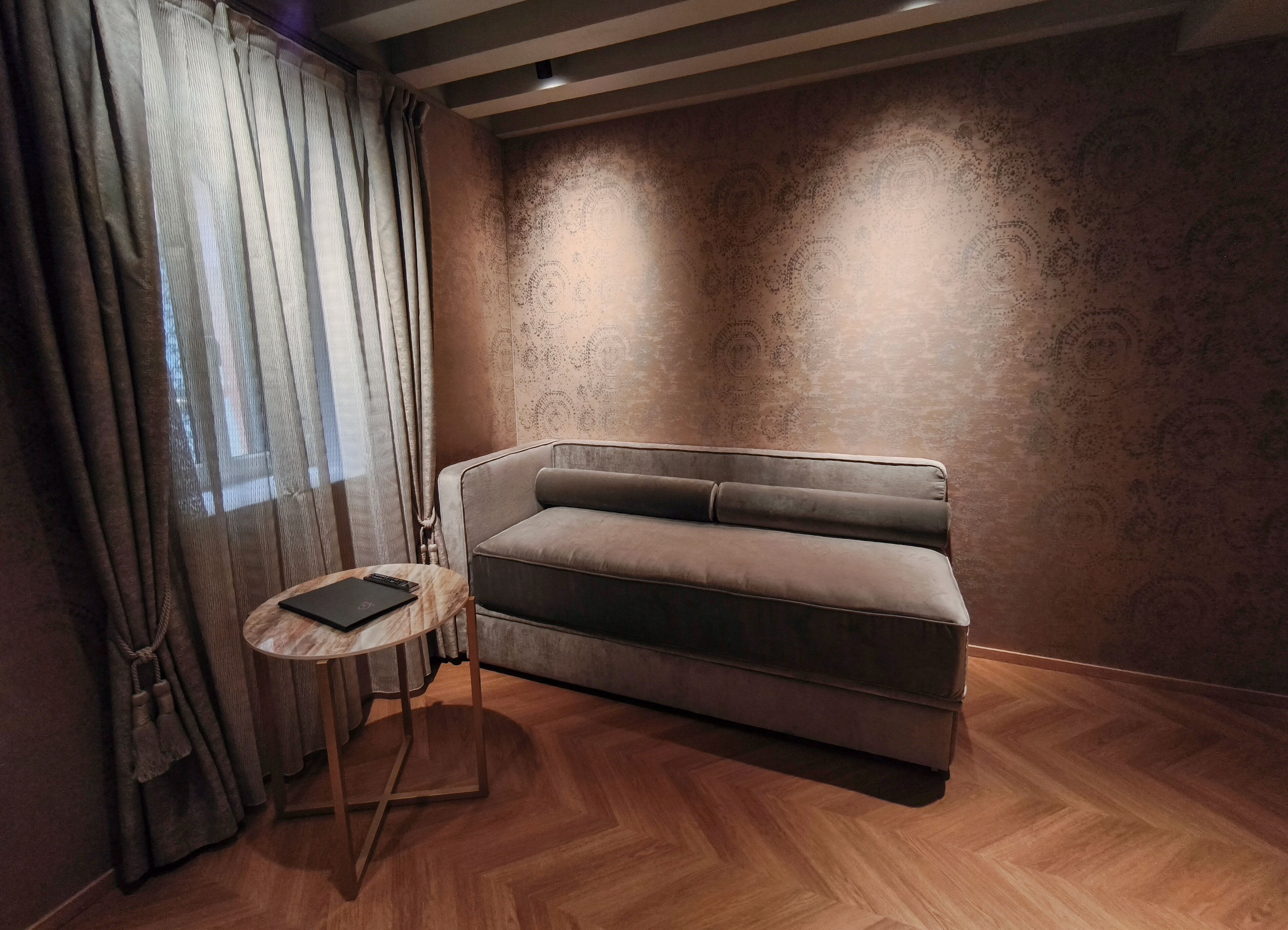 A modern room with a sofa, a small round table, and a patterned wall.