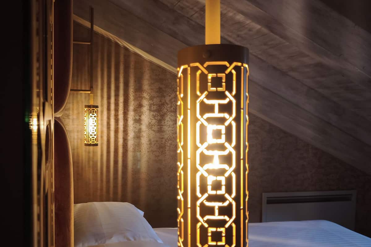 Ein Schlafzimmer mit einem Bett, einer Hängelampe und einer Wandleuchte.