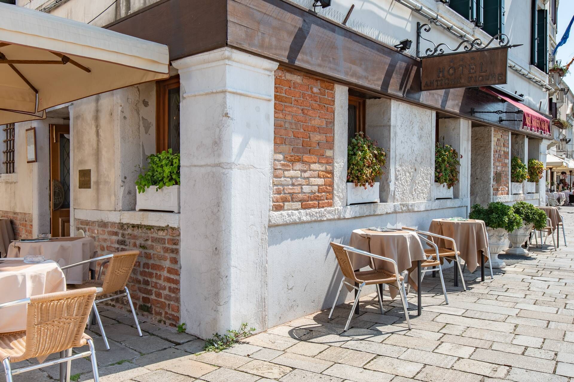 L’extérieur d’un hôtel avec des places assises en plein air, des murs en briques et des plantes suspendues.