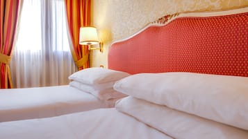 Una habitación de hotel con una cama bien hecha, una lámpara de pared y un papel tapiz estampado.