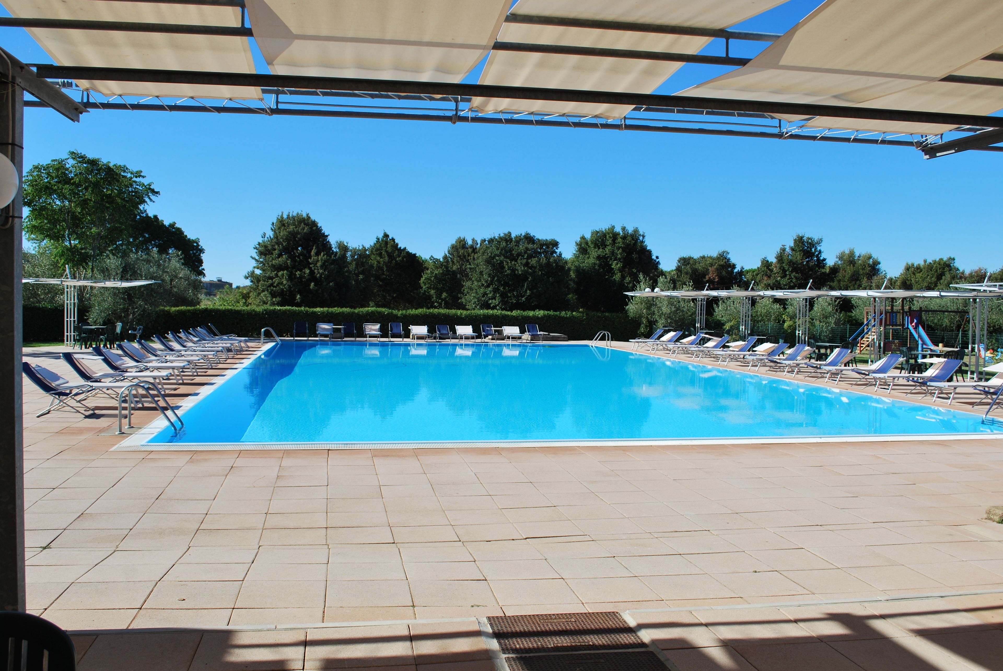 Une piscine avec des chaises longues et un espace abrité.