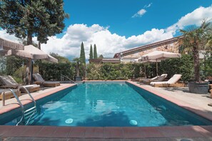 Relax by the serene pool surrounded by lush greenery and comfortable lounge chairs.