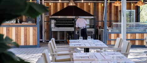 Un área de comedor al aire libre con paredes de madera y mesas dispuestas para el servicio.