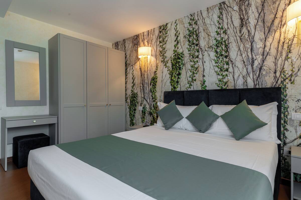 A bedroom with a bed, a desk, and a wardrobe.