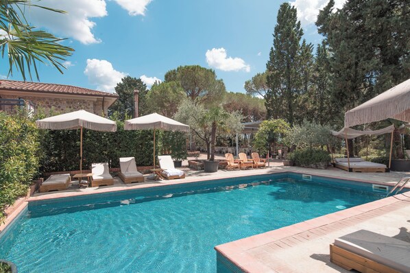 Relax by the serene pool surrounded by lush greenery and comfortable lounge chairs.