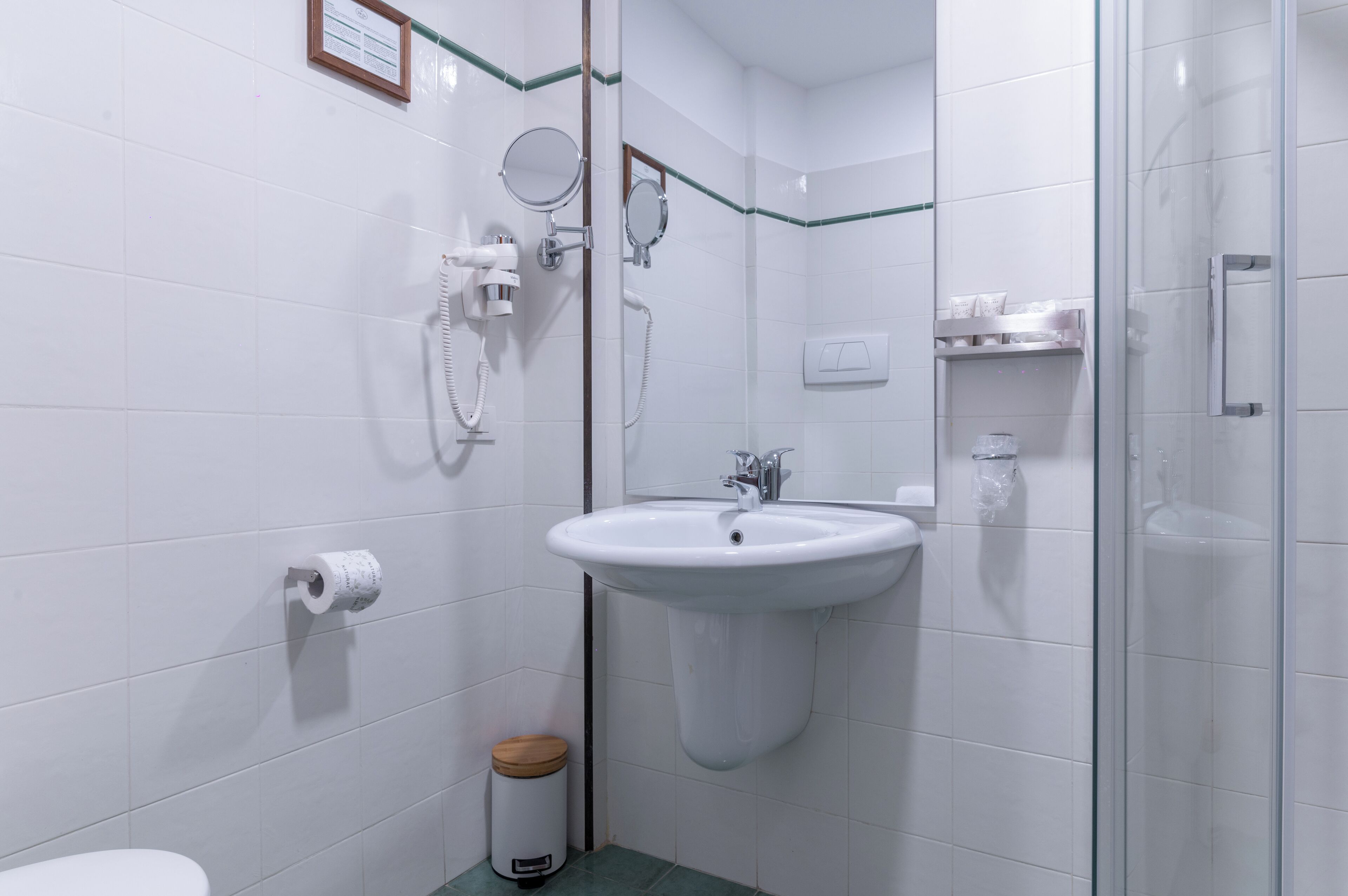 A bathroom with a sink, mirror, and shower.