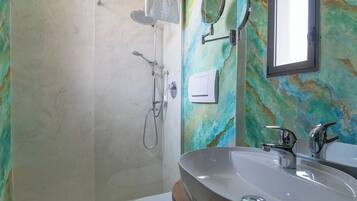 Un baño con un lavamanos grande, ducha, espejo y una pared con un diseño abstracto y colorido.