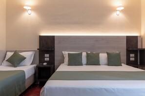 Two single beds with matching bedding, nightstands, and lamps.