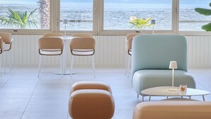 A modern interior with a view of a lake. There are chairs and a sofa arranged around a table. - Hotel Carillon (Baveno)