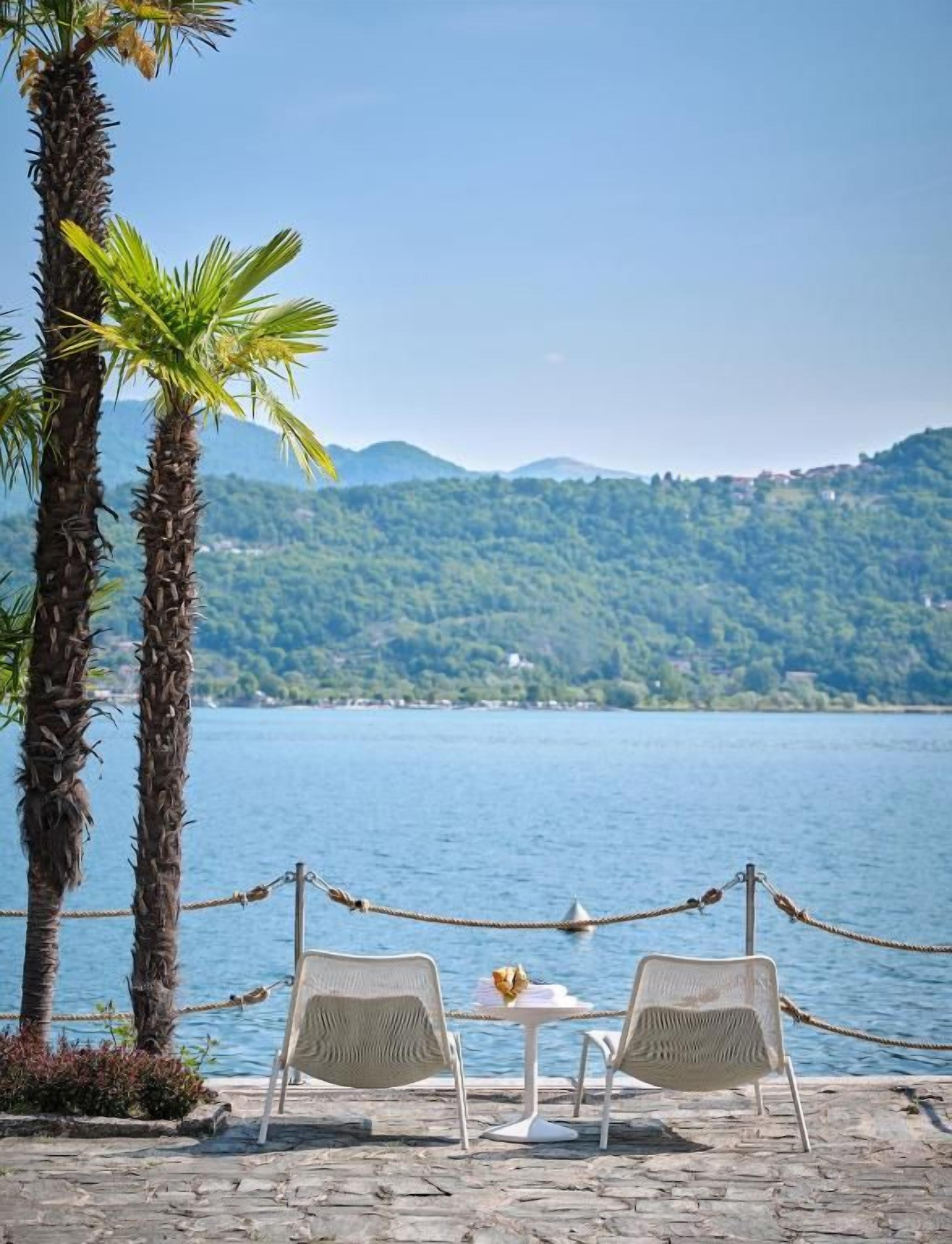 A view of a lake with two chairs and a table, surrounded by a rope barrier, with a mountain in the background.