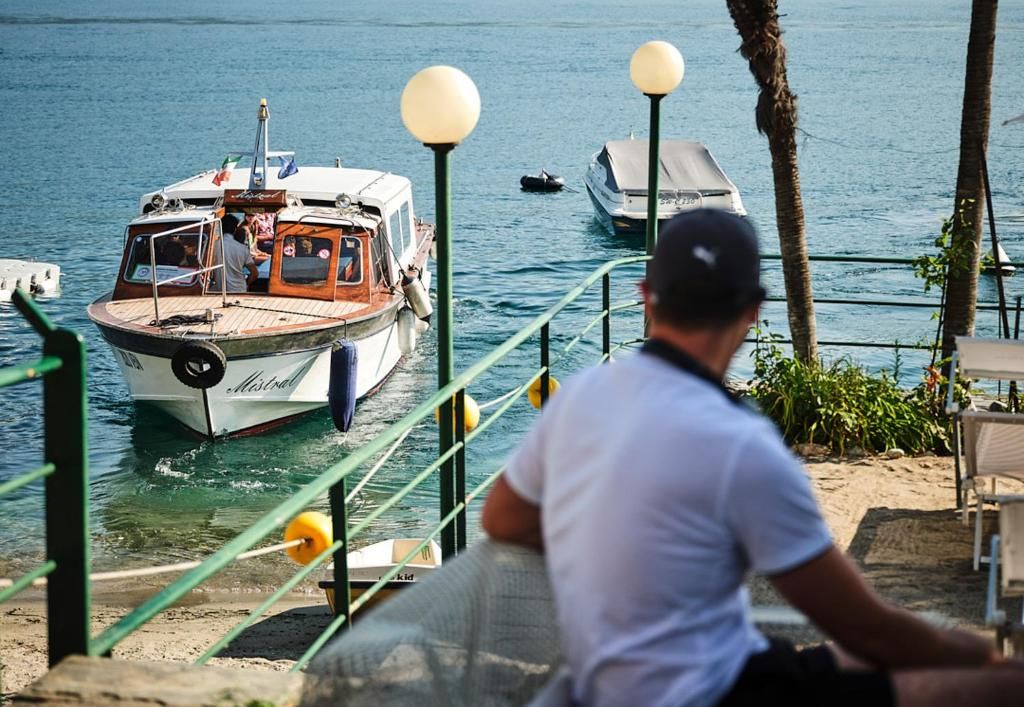 A boat docked at a pier with a person sitting on the dock.