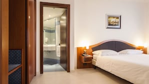 A hotel room with a bed, bedside table, and a bathroom visible through an open door. - Hotel Donizetti (Lallio)
