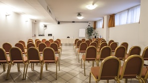 A conference room with rows of chairs, a whiteboard, and a projector. - Hotel Donizetti (Lallio)