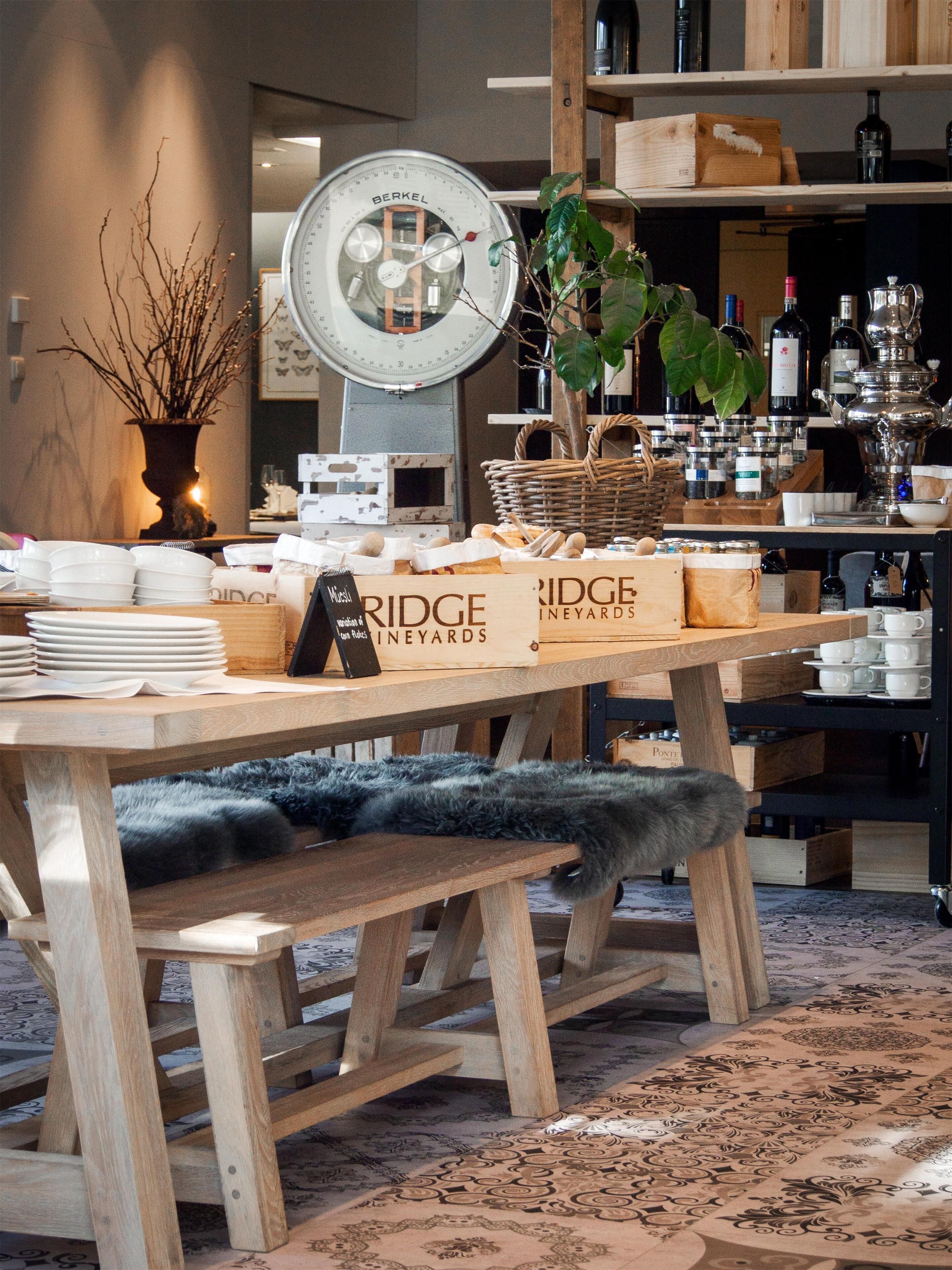 Une table en bois, avec des assiettes, une balance et un panneau indiquant « Bridge Vineyards ».