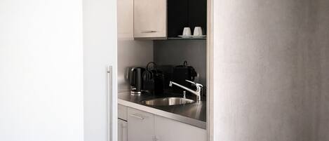 A modern kitchen with a stainless steel sink, a kettle, and a coffee maker.