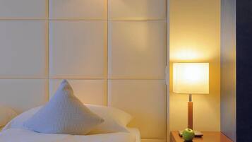 Ein Hotelzimmer mit Bett, Nachttisch mit Lampe und Wandleuchte.