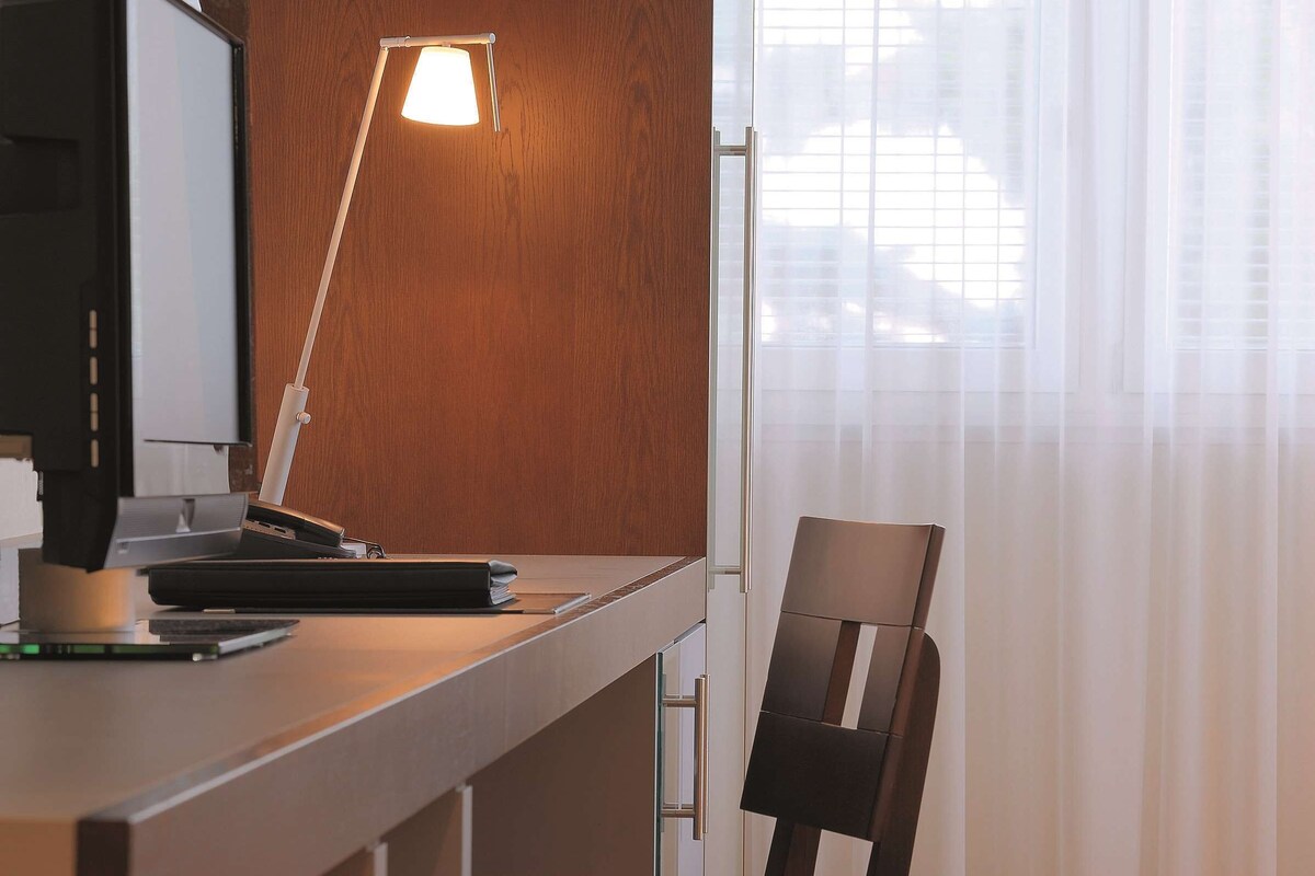 Un escritorio moderno con una computadora, una lámpara y una silla.