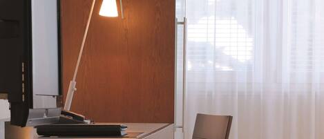 A modern office desk with a computer, a lamp, and a chair.
