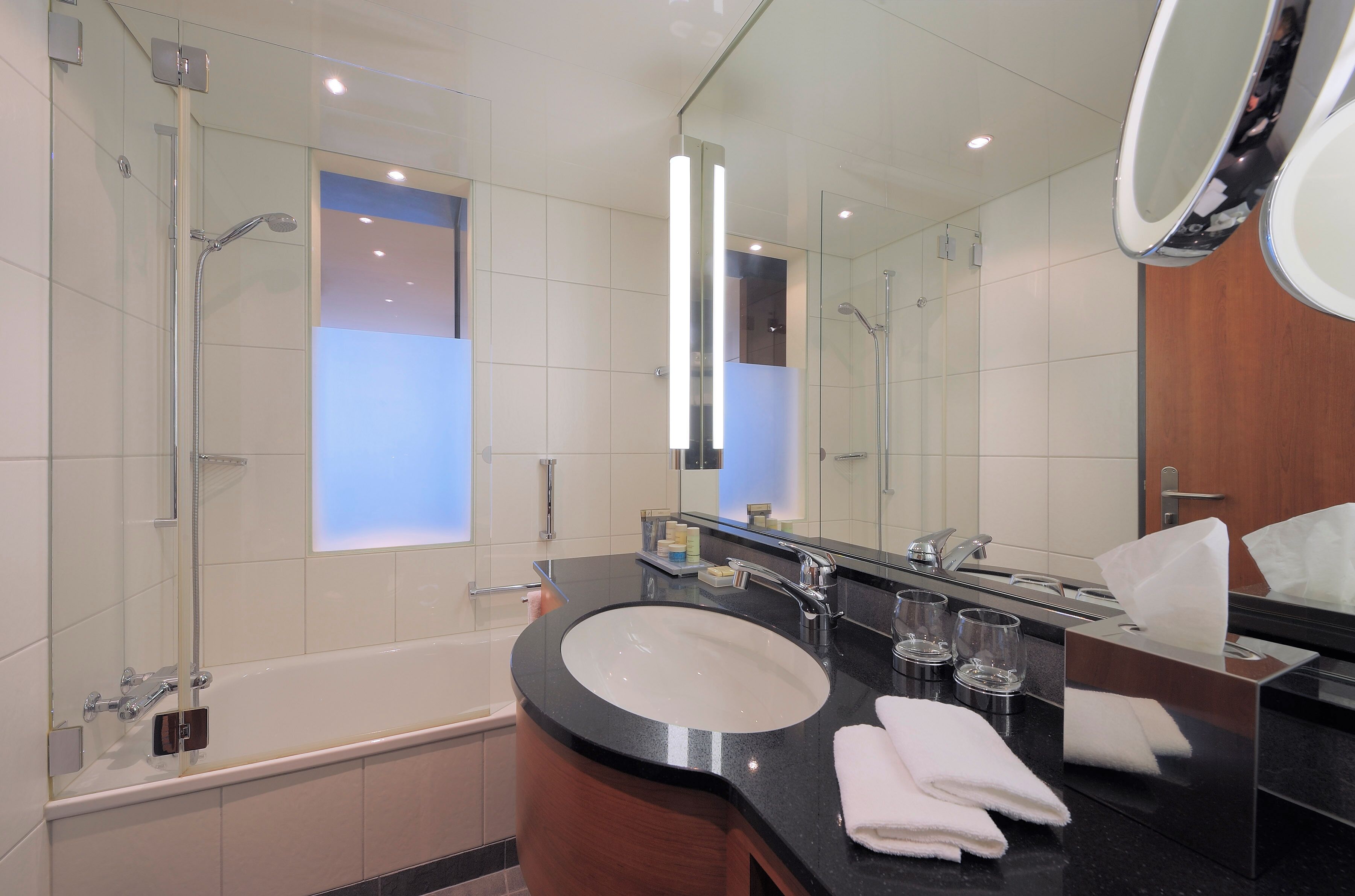 A modern bathroom with a bathtub, a sink, and a mirror.
