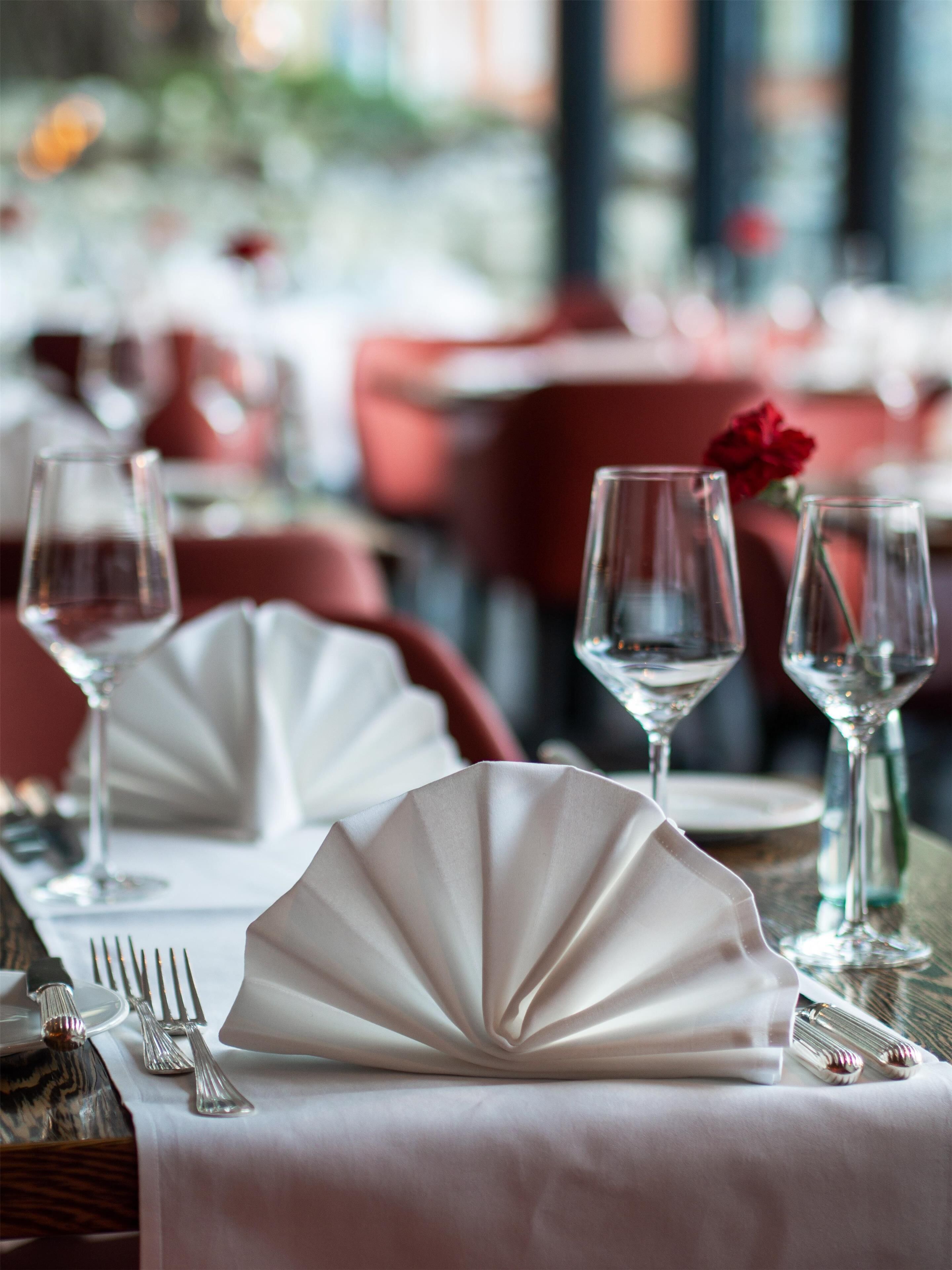 A dining table set with white napkins, wine glasses, and cutlery.