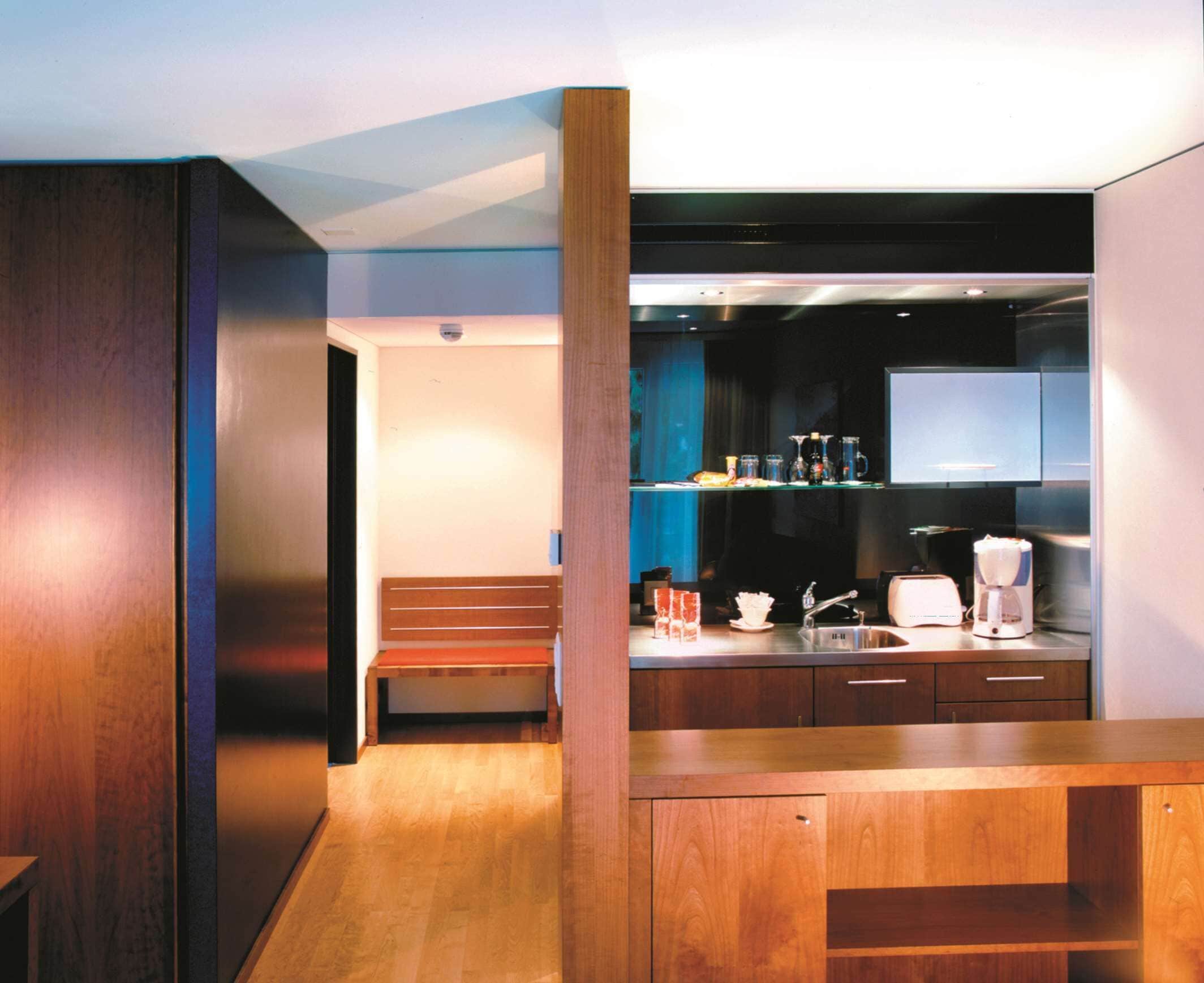 A modern kitchen with wooden cabinetry, a built-in bench, and a coffee maker.