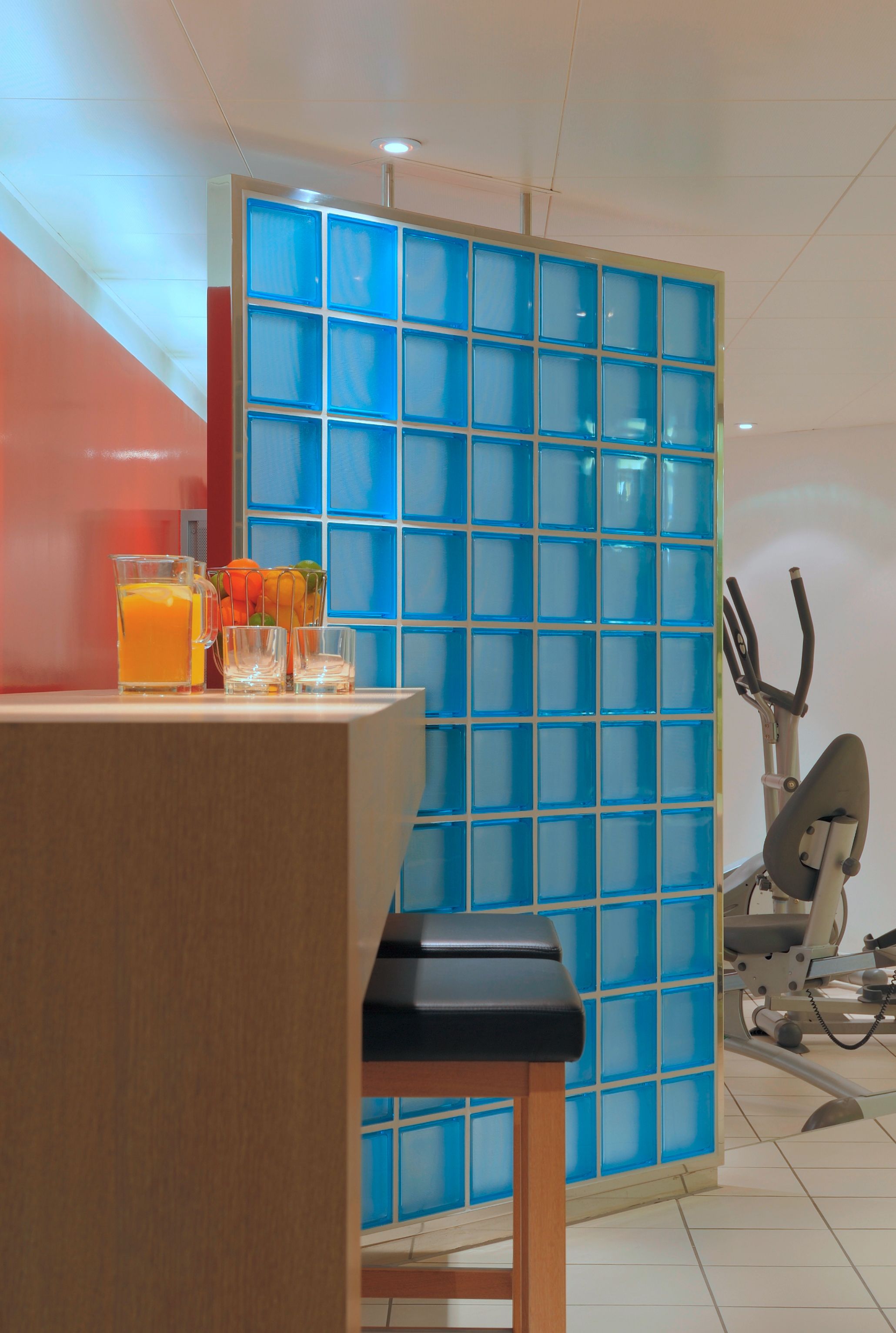 Een kamer met een houten tafel, een blauw betegelde scheiding en een hometrainer.