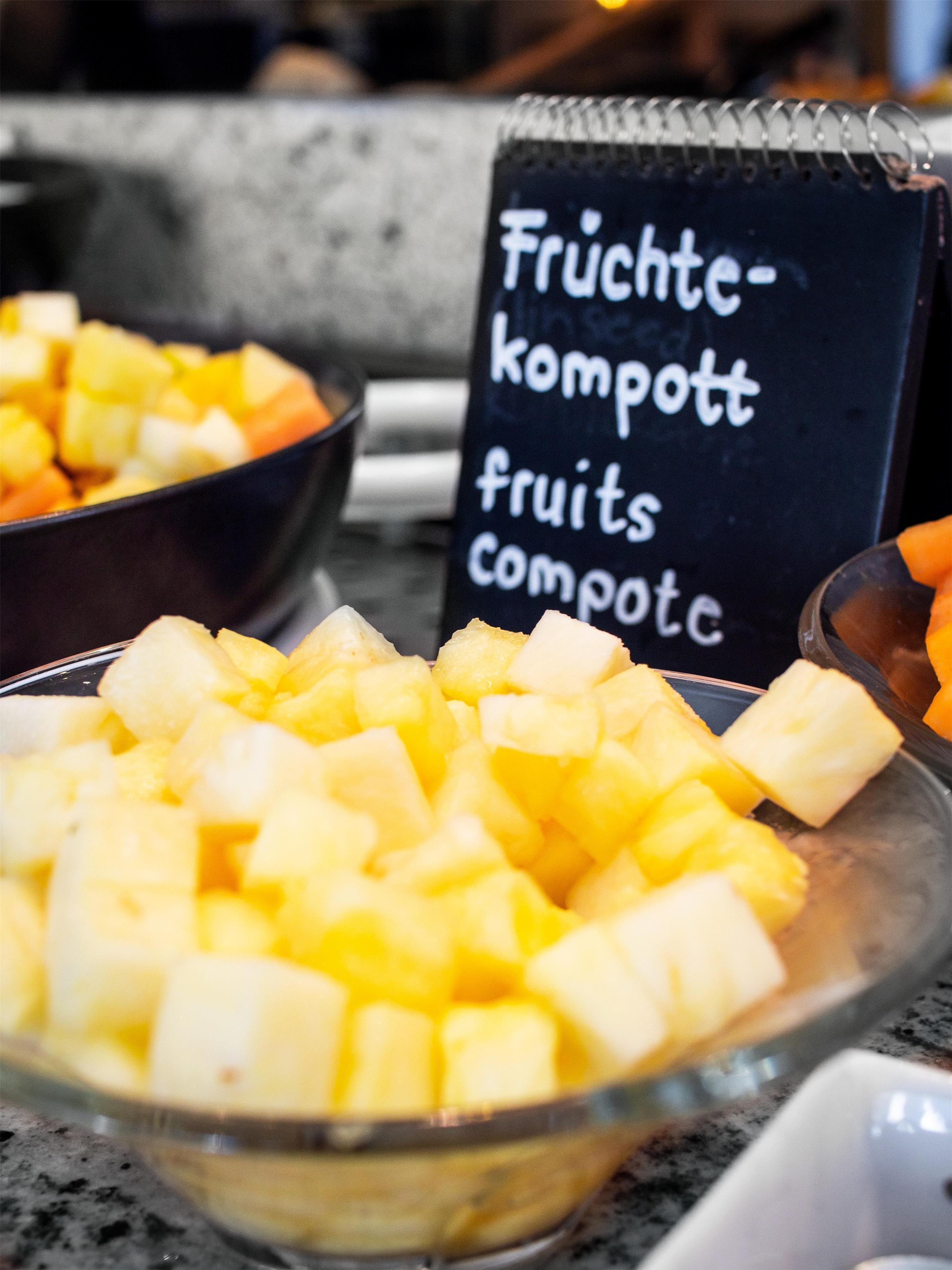 A bowl of diced fruit, a blackboard with text, and a spoon.
