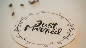 Een rond bord met de tekst 'Just Married', omringd door een decoratief bladmotief.
