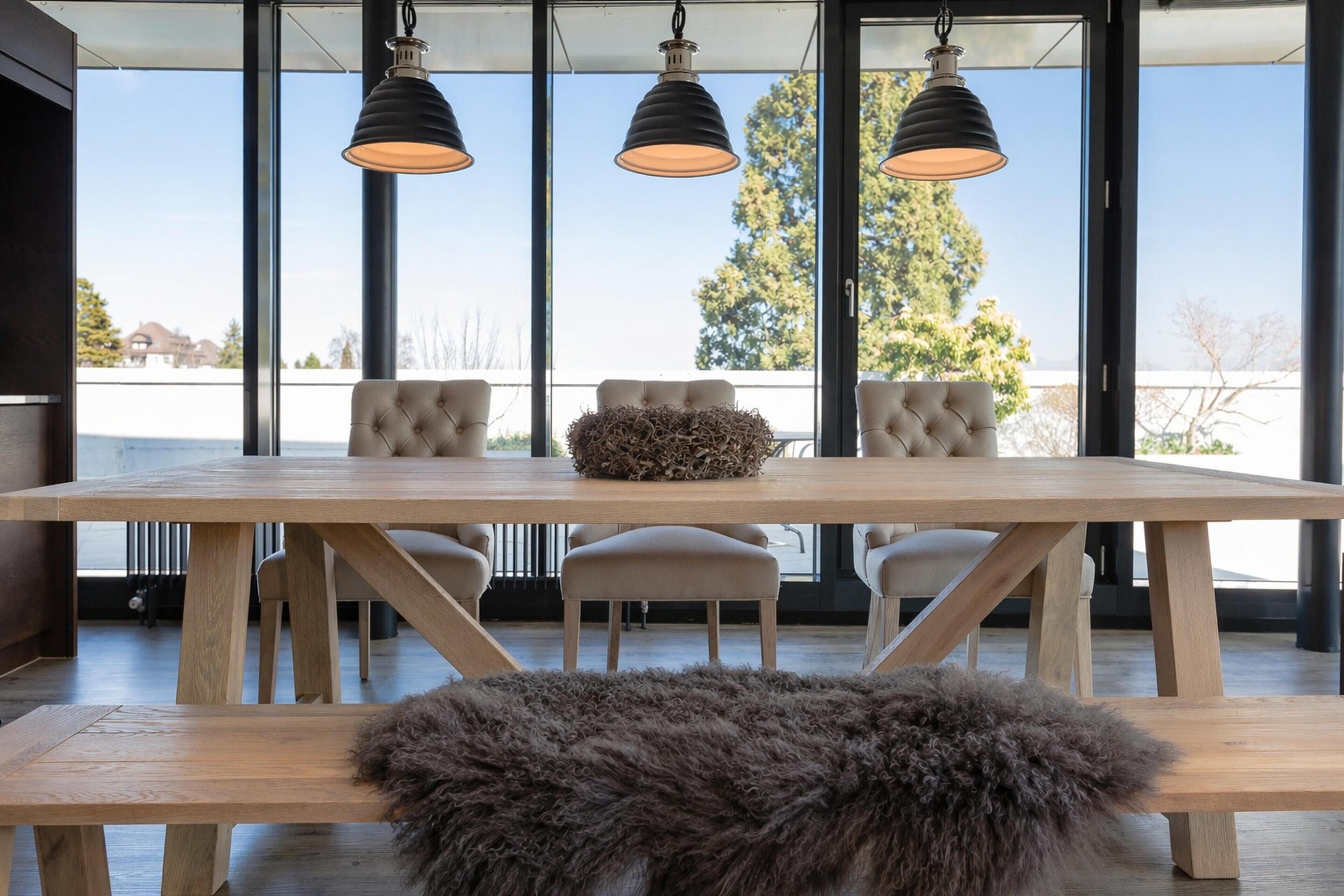 Een eetruimte met een houten tafel, gestoffeerde stoelen en hangende pendantlampen.