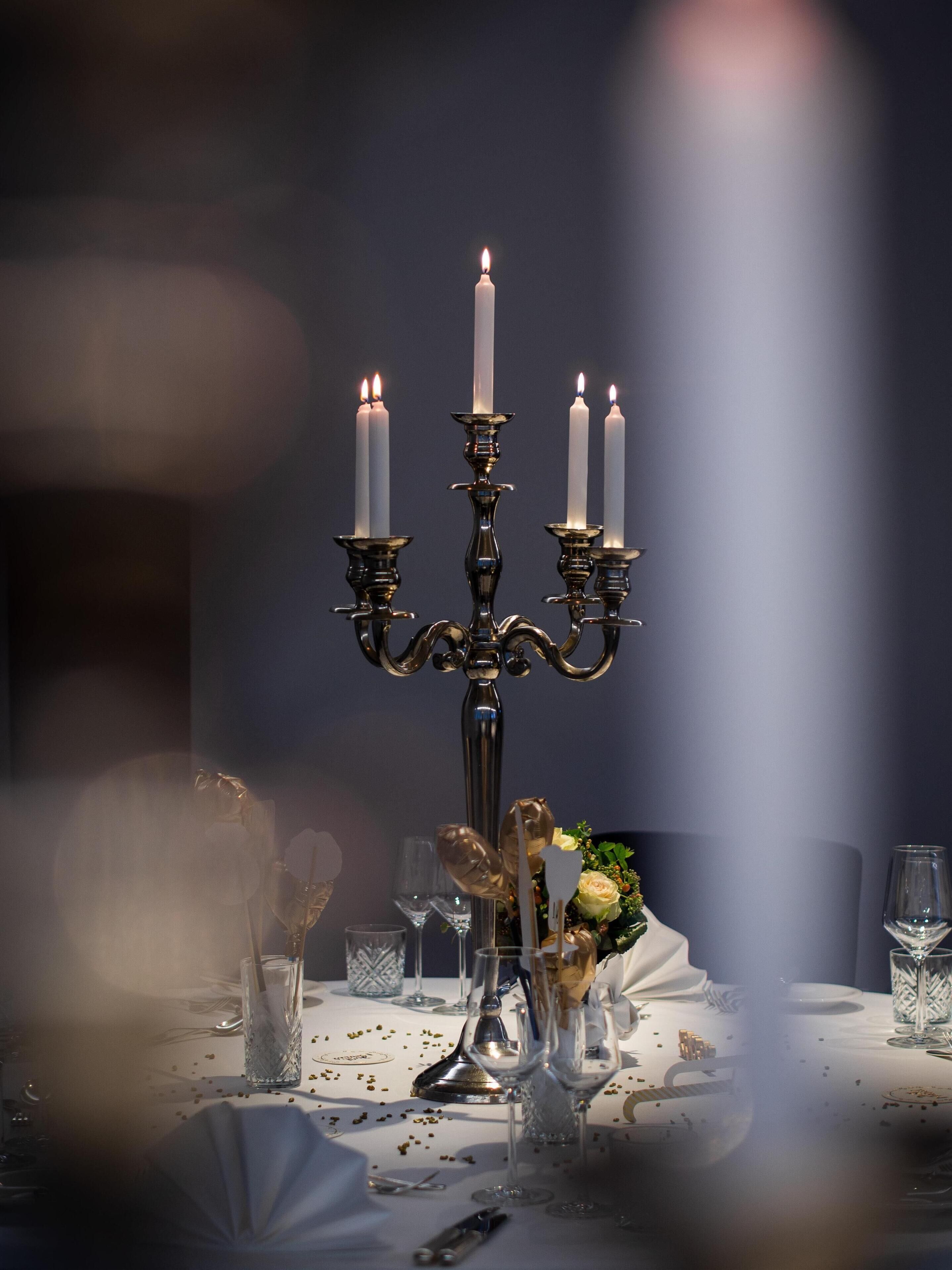 A table set with candles, glasses, and a centerpiece.