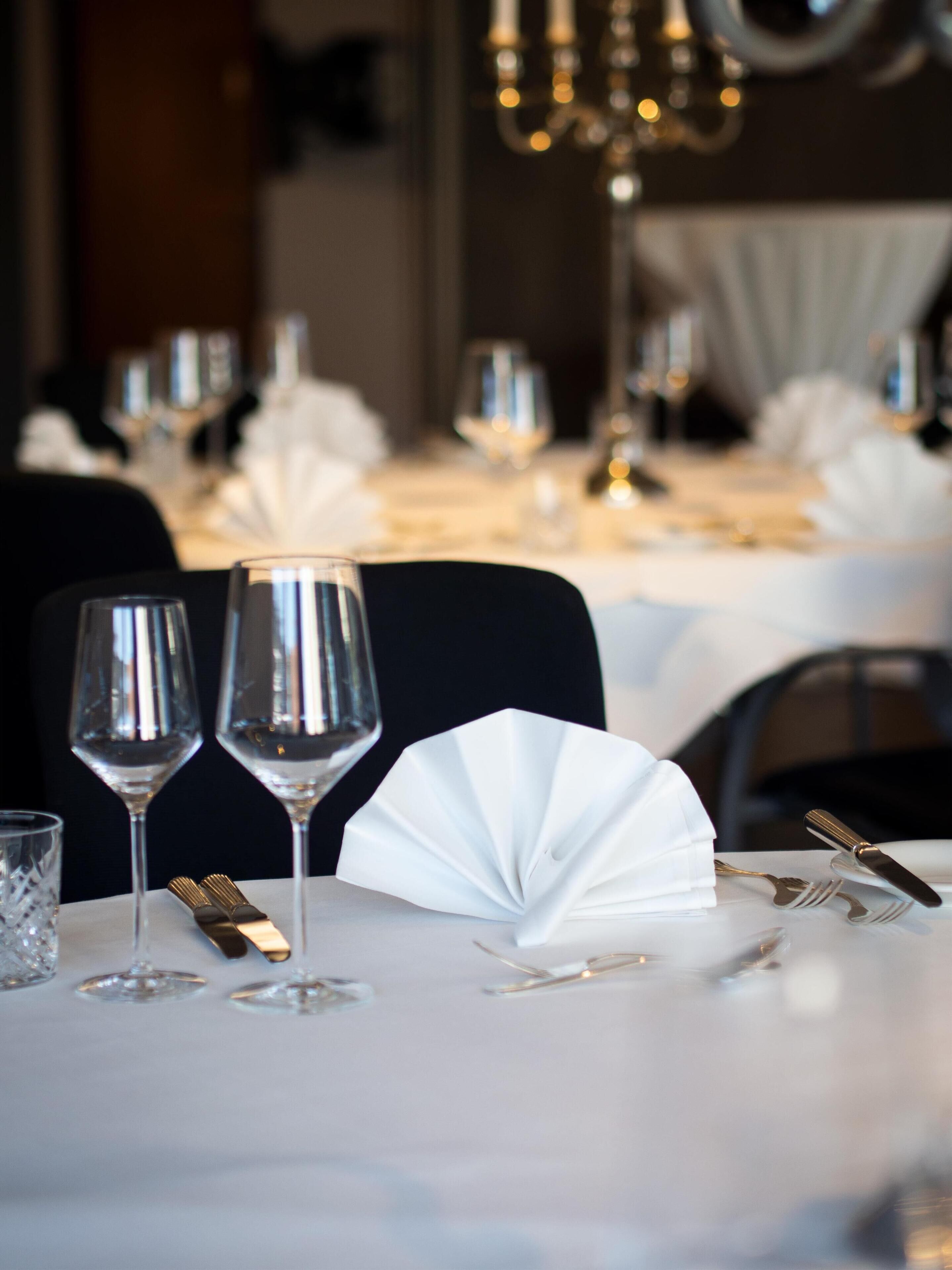 A dining table set with wine glasses, cutlery, and a folded napkin.