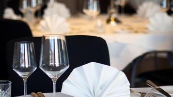 A dining table set with wine glasses, cutlery, and a folded napkin.
