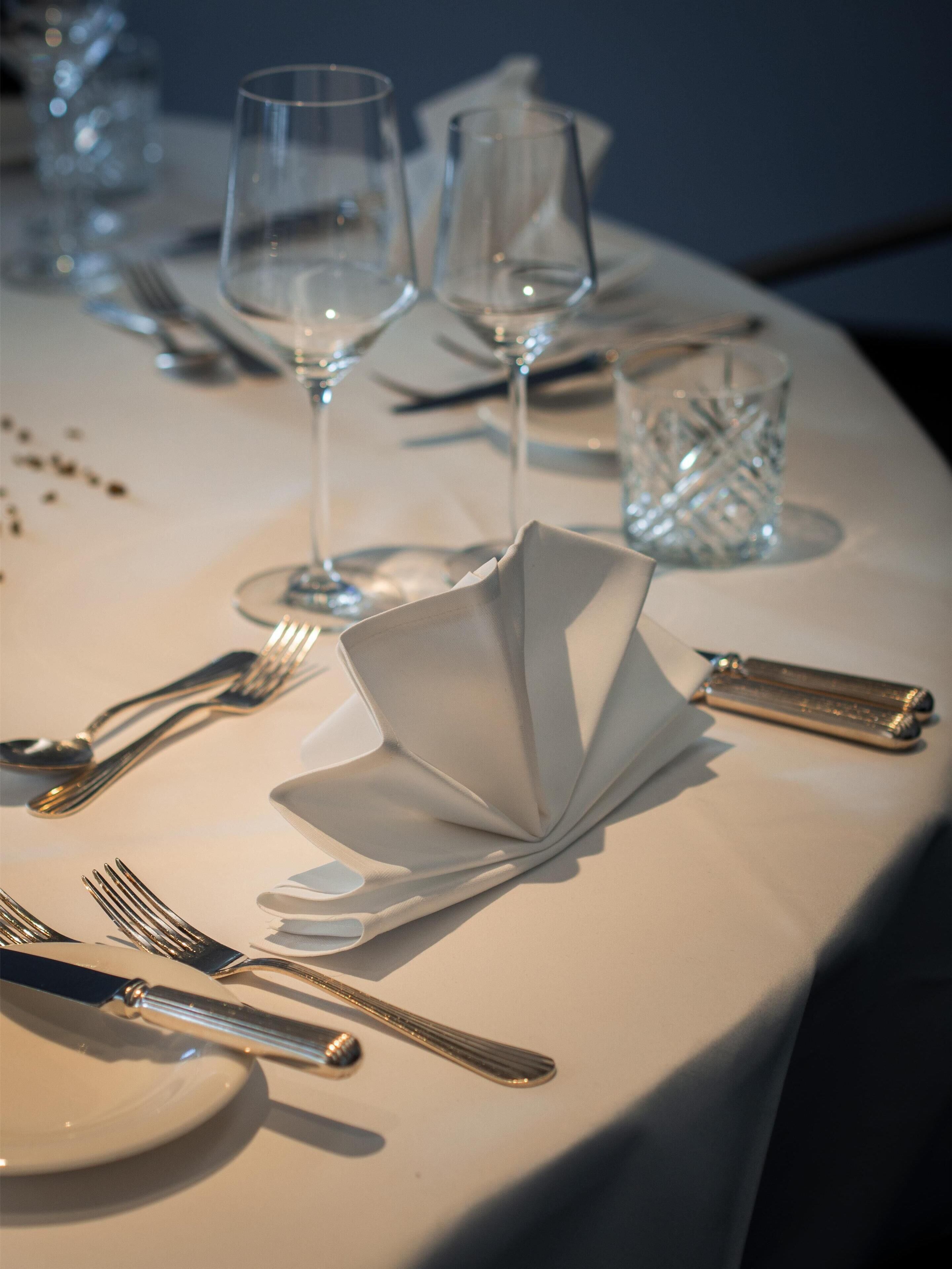 Una mesa dispuesta con cubiertos, platos y vasos, que sugiere un ambiente de comedor formal.