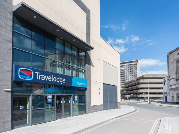 A Travelodge hotel with a modern facade, large windows, and a clear sky.