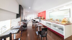 A modern restaurant with wooden tables and chairs, a buffet counter with various food items, and a bright red accent wall. - Soho Boutique Salamanca  (Salamanca)