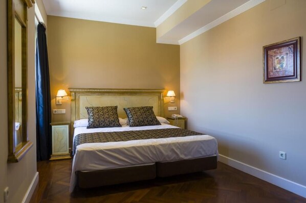 A hotel room with a large bed, two bedside lamps, a nightstand, and a framed picture on the wall.