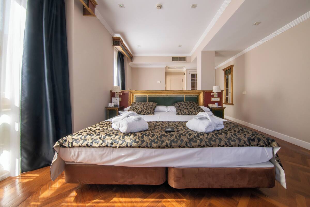 Una cama grande con un edredón estampado, dos almohadas y dos toallas.